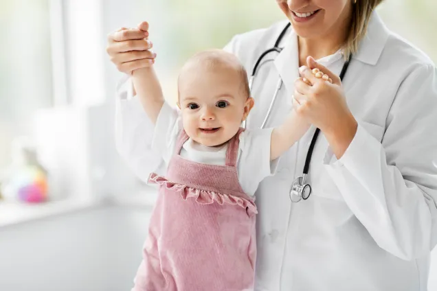 baby in pink held by smiling doctor 